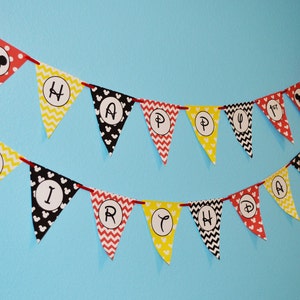 May include: A red, yellow, and black Happy Birthday banner with Mickey Mouse ears and a Mickey Mouse head on one of the flags.
