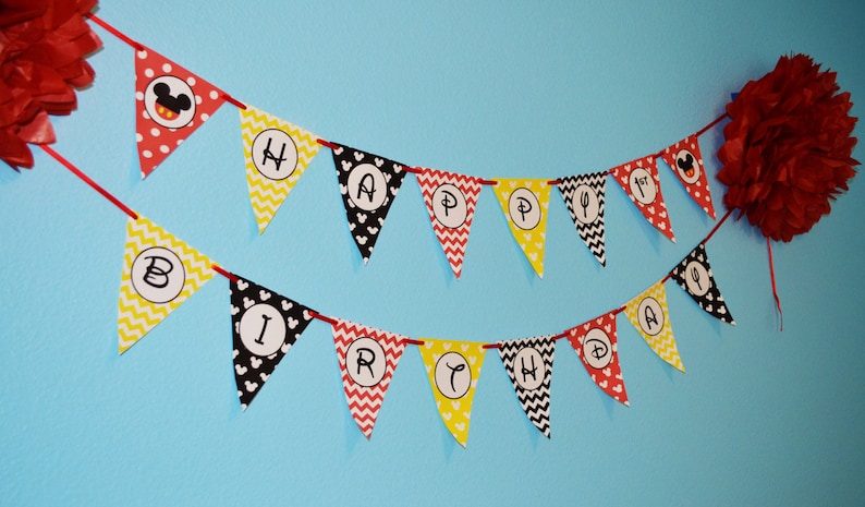 May include: A red, yellow, and black Happy Birthday banner with Mickey Mouse ears and a Mickey Mouse head on one of the flags.