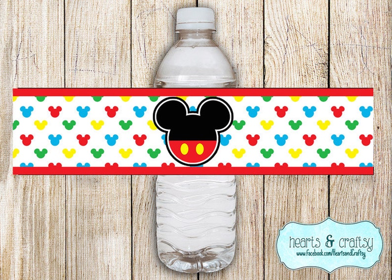 May include: Water bottle label featuring Mickey Mouse with red, yellow, blue, and green Mickey Mouse ears on a white background. The label has a red border and the text "hearts & crafty" is visible at the bottom.