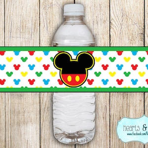 May include: Water bottle label featuring a Mickey Mouse head with red and black accents. The background is white with a repeating pattern of red, yellow, blue, and green Mickey Mouse ears.