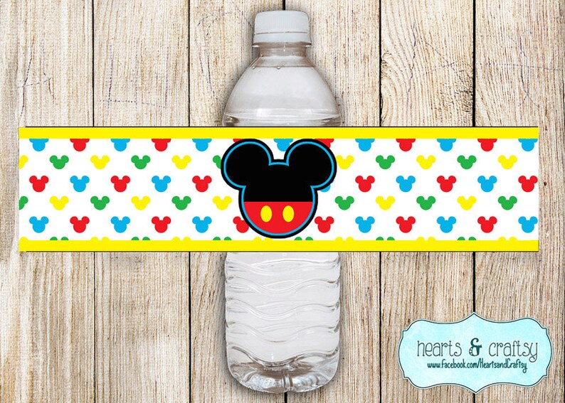 May include: Water bottle label featuring Mickey Mouse with red, yellow, blue, and green polka dots. The label has a yellow border and the text "hearts & crafty" with a website address.