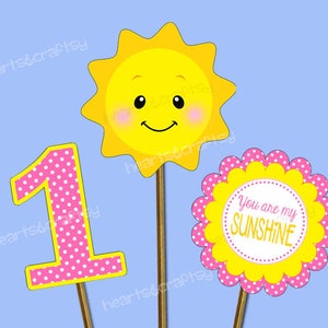Pu&ograve; includere: Tre sagome di carta gialla, rosa e bianca con pois. La sagoma del sole ha un viso sorridente. Le altre due sagome sono un numero uno e un cerchio con il testo "You are my sunshine".