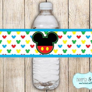 May include: A blue and white printable water bottle label with a Mickey Mouse head in the center. The label features a repeating pattern of colorful Mickey Mouse ears.