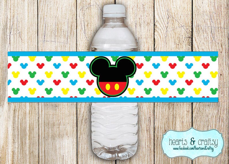 May include: A blue and white printable water bottle label with a Mickey Mouse head in the center. The label features a repeating pattern of colorful Mickey Mouse ears.