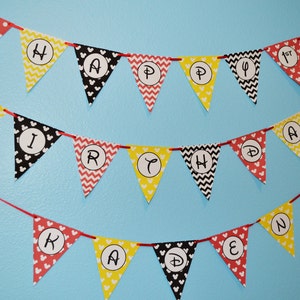 May include: A red, yellow, and black Mickey Mouse themed banner with the words "Happy 1st Birthday Kaden".