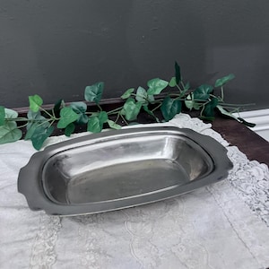 Może przedstawiać: Srebrna prostokątna tacka do serwowania z lekko uniesionym brzegiem i gładką, polerowaną powierzchnią. Tacka leży na białym obrusie z koronki.