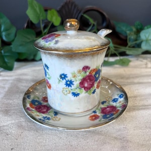 May include: A white ceramic mug with a black handle and the text "But First, Coffee" in a black, bold font. The mug is on a white surface.