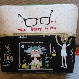 Può includere: Una pochette con zip nera e bianca con sfondo bianco e pois neri. La pochette ha una zip verde e il testo "Talk Nerdy to Me" ricamato in rosso. La parte anteriore della pochette presenta uno scienziato dei cartoni animati con i capelli blu e un camice da laboratorio, che tiene un becher e un microscopio. Lo scienziato è circondato da attrezzature di laboratorio, tra cui becher, matracci e provette.