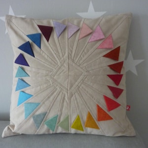May include: A white pillow with a colorful geometric design. The pillow is made of fabric and has a variety of colors, including red, orange, yellow, green, blue, indigo, and violet. The pillow is perfect for adding a pop of color to any room.