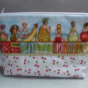 Peut inclure: Une pochette blanche à fermeture éclair avec un imprimé coloré de femmes en maillot de bain sur une plage. L'imprimé comprend des cerises, des ananas et des palmiers. Le bas de la pochette a un fond blanc avec un motif répétitif de cerises rouges.