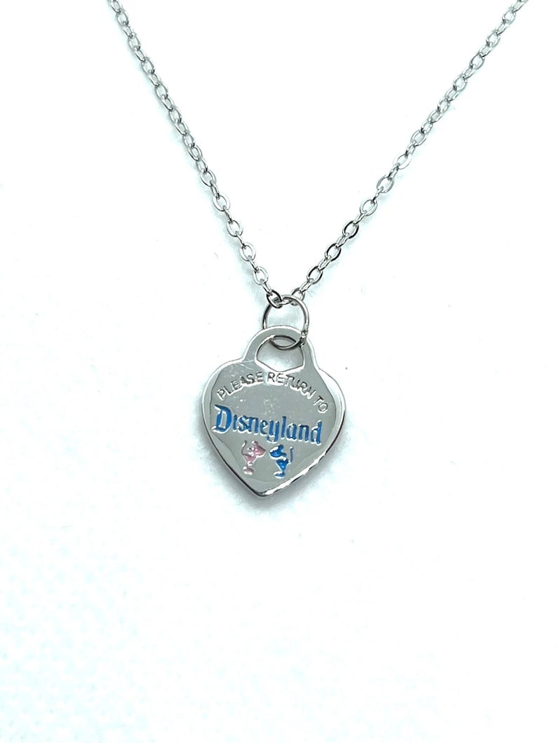 May include: Silver heart-shaped necklace with a silver chain. The pendant has the text "Please return to Disneyland" with a pink and blue Mickey Mouse silhouette.