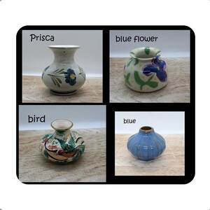 May include: A collection of four small ceramic vases. The top left vase is labelled Prisca and features blue flowers. The top right vase is labelled blue flower and has green and purple patterns. The bottom left vase is labelled bird and has colourful bird motifs. The bottom right vase is labelled blue and has a ribbed texture.