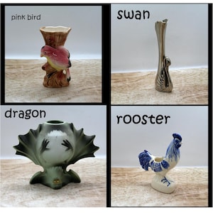 Op de afbeelding: Vier keramische beeldjes: een roze vogel, een zwaan, een draak en een haan. De roze vogel zit op een bruine vaas. De zwaan is een hoge, slanke vaas. De draak is groen met een uitlopende voet. De haan is blauw en wit.
