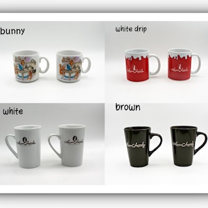 May include: A collection of coffee mugs in various styles and colors. The mugs include a bunny design, white drip design, solid white, and solid brown. Each mug has a handle and a logo. The mugs are displayed on a white background.
