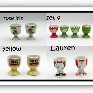 May include: A collection of ceramic egg cups in various designs. The cups include floral, geometric, and cartoon-like patterns. The text "rose iris", "set 4", "yellow", and "Lauren" are visible.