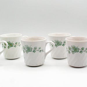 May include: Six white ceramic mugs with a green ivy leaf design. The mugs have a spiral texture and a handle. The mugs are suitable for hot or cold drinks.