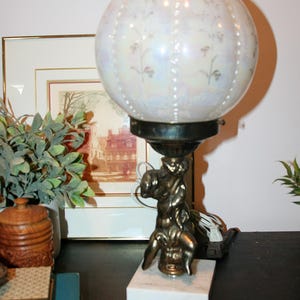 Vintage 1970s gold metal cherub baby lamp with marble base and round milk glass globe with gold accent detail,  Hollywood Regency style lamp