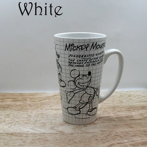 May include: White ceramic Mickey Mouse mug with a black and white sketch design. The mug features the text "MICKEY MOUSE" and a quote about the character's chest and mood. The mug has a tall, slender shape and a curved handle.