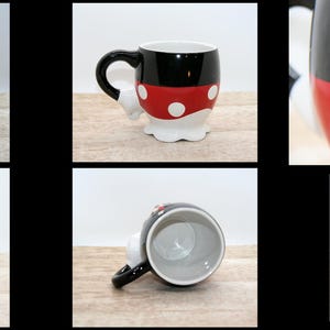 May include: A ceramic mug featuring a design inspired by a popular cartoon character. The mug has a black top, a red midsection with white polka dots, and a white base. The handle is black, and the base is shaped like the character's gloves.