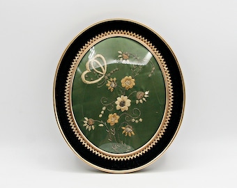 Vintage wanddecoratie met goudborduurwerk, ovale lijst met vlinders en bloemen van gouden draad en een zwarte fluwelen rand, sierlijke Victoriaanse woondecoratie.