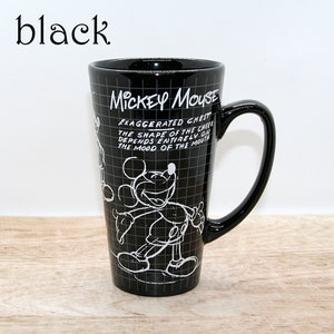 May include: Black ceramic Mickey Mouse mug with a large handle. The mug features a white outline drawing of Mickey Mouse and text that reads "MICKEY MOUSE" and "EXAGGERATED CHEST...THE MOOD OF THE MOUTH". The mug is tall and cylindrical.