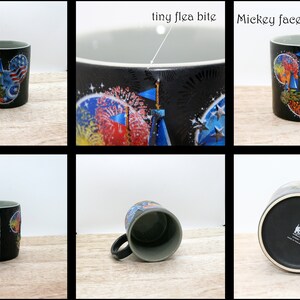 May include: Black ceramic mug with a gray interior and a curved handle. The mug features a colorful design of a Mickey Mouse face with an American flag theme, fireworks, and a castle. The mug has the words "Walt Disney World" on the side.