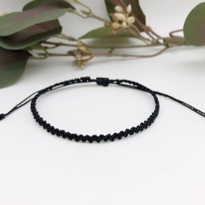 Puede incluir: Una pulsera trenzada negra simple con longitud ajustable.