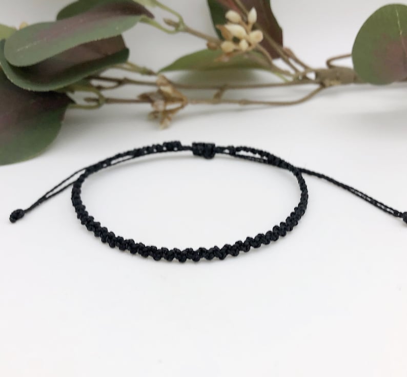 Puede incluir: Una pulsera trenzada negra simple con longitud ajustable.