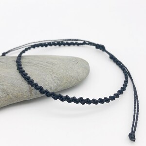 Puede incluir: Un brazalete sencillo de cord&oacute;n trenzado negro. El brazalete est&aacute; hecho de un cord&oacute;n fino y negro que se trenza para crear un look delicado y elegante.