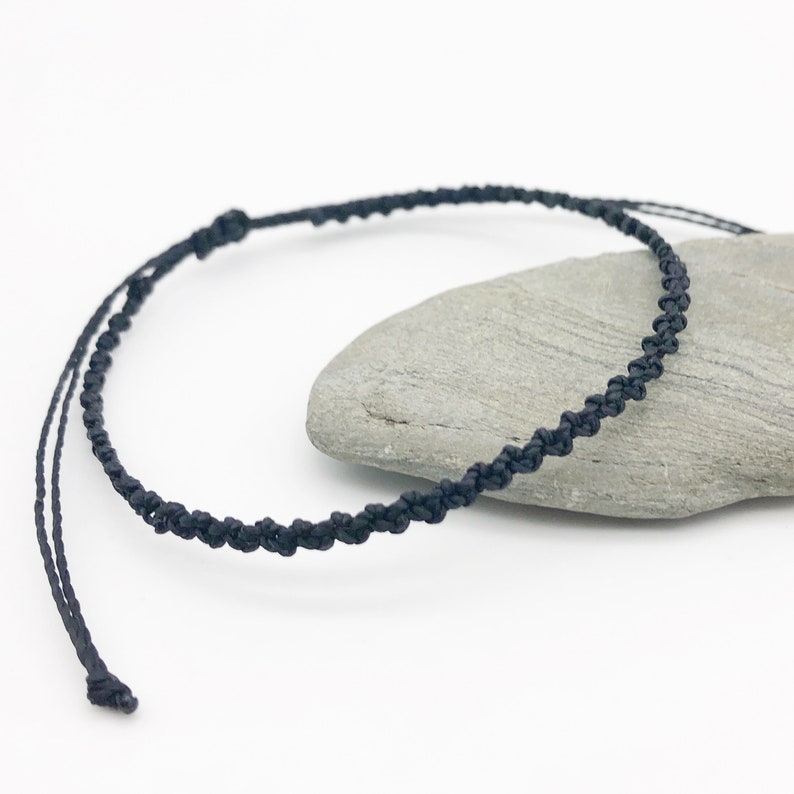 Puede incluir: Un collar de cord&oacute;n trenzado negro con un cierre simple de nudo. El collar est&aacute; hecho de cord&oacute;n fino y mide aproximadamente 45 cm de largo.