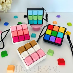 Könnte beinhalten: Ein Set aus drei Keramikbechern mit gesprenkelter, matter Oberfläche. Die Becher sind in Creme-, Hellgrau- und Dunkelgrautönen gehalten. Jeder Becher hat ein schlichtes, minimalistisches Design.