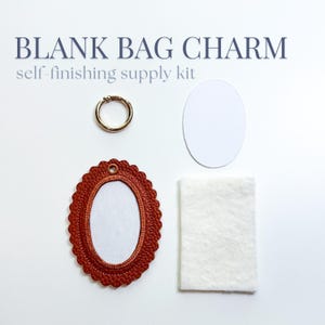 May include: A blank bag charm self-finishing supply kit featuring a scalloped-edge rust-coloured oval frame, a gold-toned metal ring, a white oval insert, and a rectangular piece of white felt material for crafting and assembly projects.