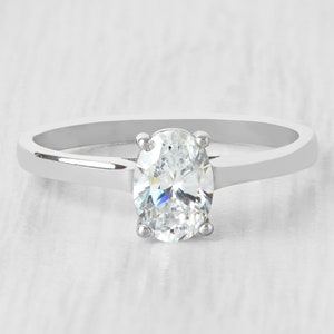 May include: A silver ring with a large oval-shaped clear gemstone.