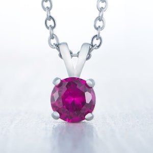 May include: A silver chain necklace with a round, bright pink gemstone pendant.