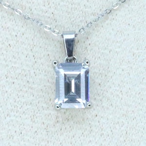 May include: A silver chain necklace with a square-shaped pendant featuring a large, clear cubic zirconia stone.