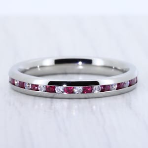May include: A silver band ring with a row of small red and white gemstones.
