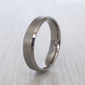 Può includere: Una fede nuziale in argento con un bordo smussato e una finitura spazzolata.