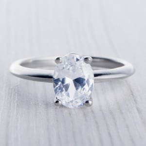 May include: A silver ring with a large, clear oval-shaped gemstone.