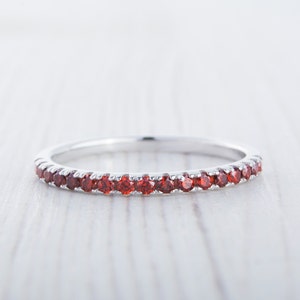 May include: A silver band ring with a row of small red gemstones.