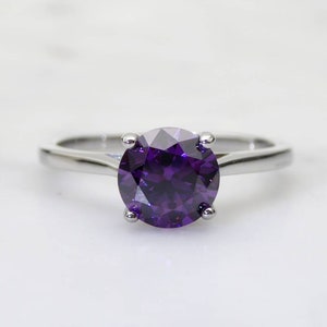 May include: A silver ring with a large, round, purple gemstone.