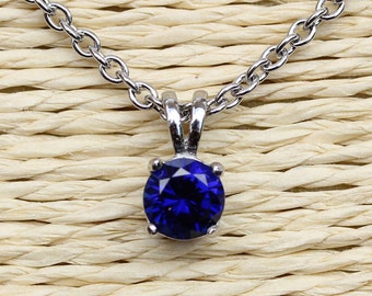 May include: A silver chain necklace with a blue gemstone pendant.
