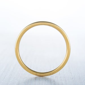 May include: A simple gold band ring.