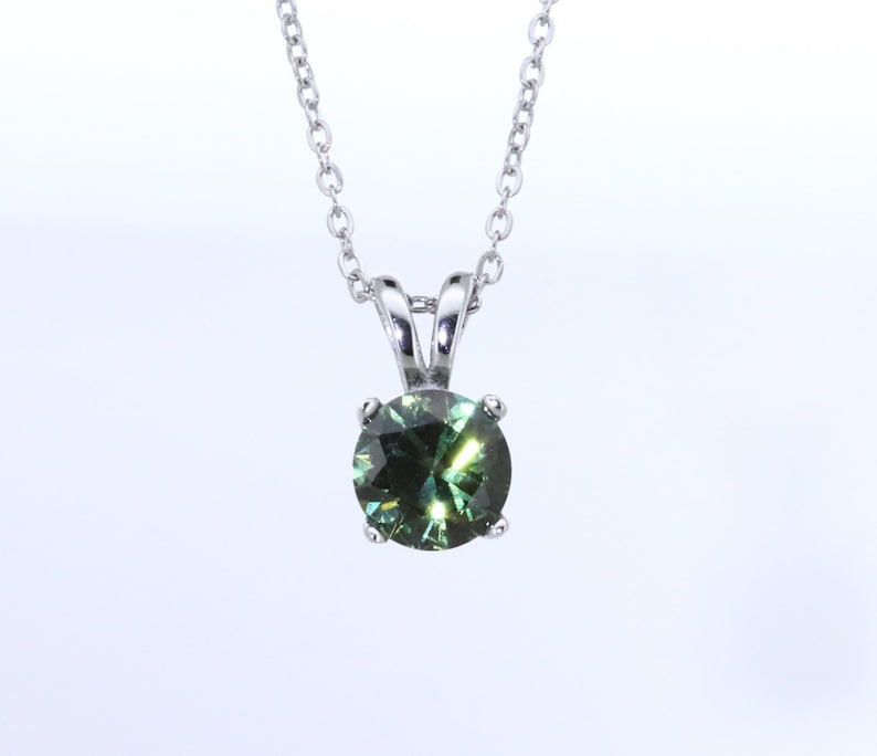 May include: A silver chain necklace with a round green gemstone pendant.