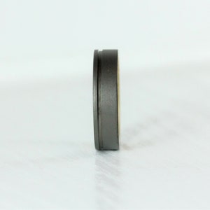 Puede incluir: Un anillo de metal gris con un borde biselado y un acabado liso.