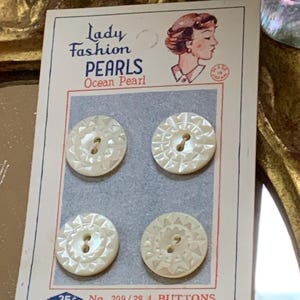 May include: Vintage card of four "Lady Fashion Pearls" buttons, labeled "Ocean Pearl." The buttons are round, off-white, and have a starburst design around the edges. The card features an illustration of a woman and the text "25¢ No. 209/28 4 BUTTONS."