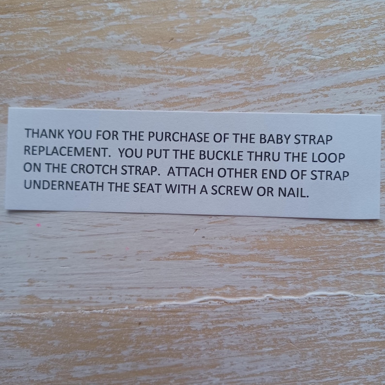 Puede incluir: Una tarjeta de instrucciones rectangular de papel blanco con texto negro que dice: THANK YOU FOR THE PURCHASE OF THE BABY STRAP REPLACEMENT. YOU PUT THE BUCKLE THRU THE LOOP ON THE CROTCH STRAP. ATTACH OTHER END OF STRAP UNDERNEATH THE SEAT WITH A SCREW OR NAIL.