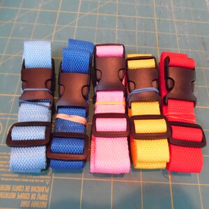 Puede incluir: Cinco correas de nailon ajustables en azul claro, azul real, rosa, amarillo y rojo. Cada correa cuenta con una hebilla de liberaci&oacute;n lateral de pl&aacute;stico negro y un ajustador deslizante de pl&aacute;stico negro, aseguradas con peque&ntilde;as bandas el&aacute;sticas.