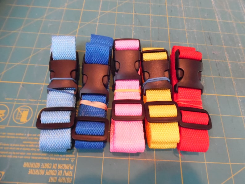Puede incluir: Cinco correas de nailon ajustables en azul claro, azul real, rosa, amarillo y rojo. Cada correa cuenta con una hebilla de liberaci&oacute;n lateral de pl&aacute;stico negro y un ajustador deslizante de pl&aacute;stico negro, aseguradas con peque&ntilde;as bandas el&aacute;sticas.