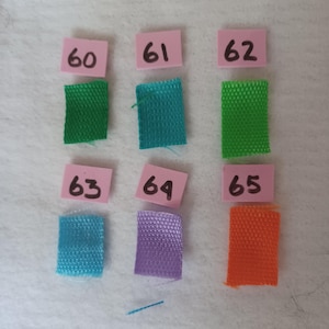 Puede incluir: Seis muestras de tela rectangulares en verde, verde azulado, verde lima, azul claro, morado y naranja, cada una emparejada con una peque&ntilde;a etiqueta cuadrada rosa con los n&uacute;meros 60, 61, 62, 63, 64 y 65 escritos a mano, dispuestos en dos filas.