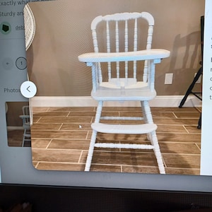 Puede incluir: Una trona de madera blanca con un dise&ntilde;o de respaldo de husillos, una bandeja plana, un asiento y un reposapi&eacute;s. La silla est&aacute; construida con patas torneadas y travesa&ntilde;os de soporte, proporcionando una estructura estable con un acabado uniforme.